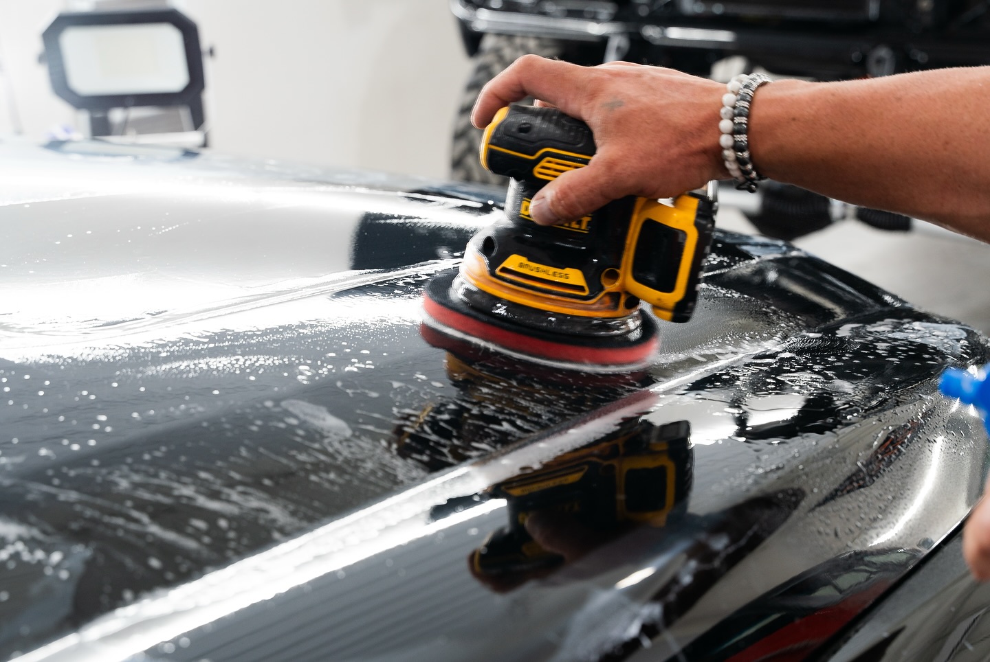 Orbital polisher on a black panel during paint correction