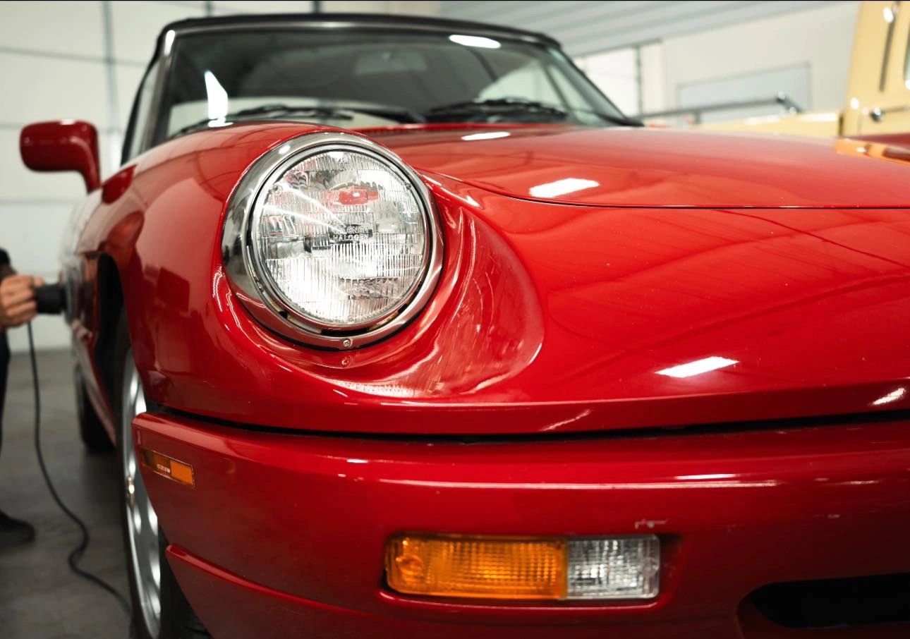 Clear, restored headlight on a red Porsche